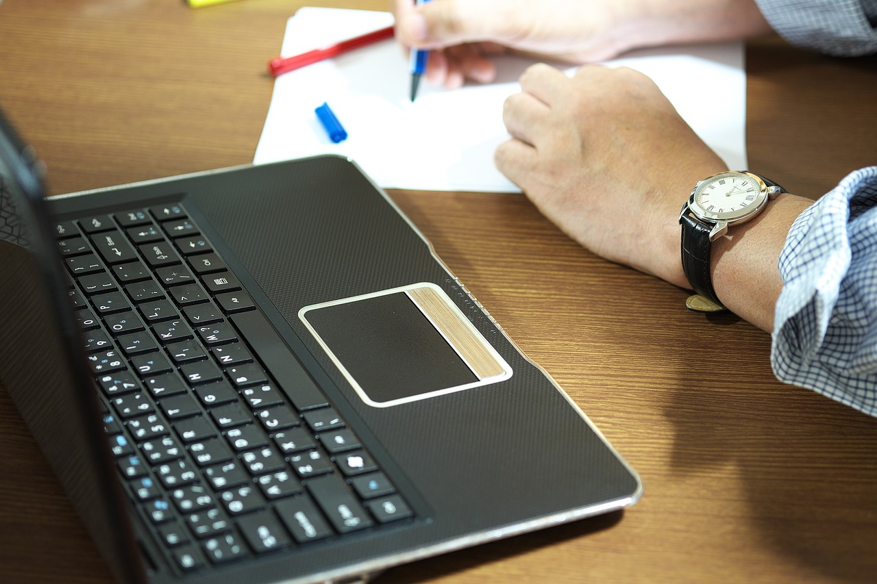 How to Retrieve Your Canada eTA Details If You've Lost Them: person writing on paper next to a laptop
