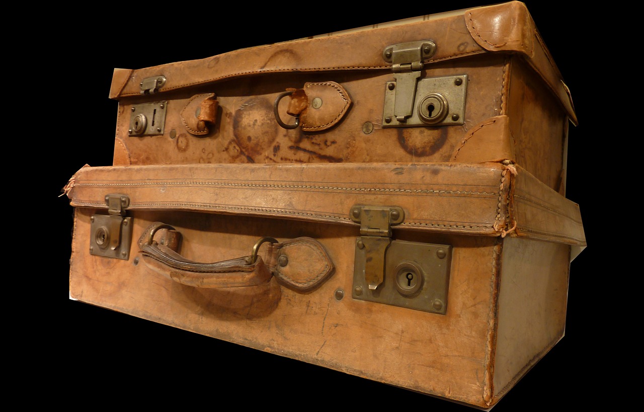 Two vintage leather suitcases stacked against a black background.