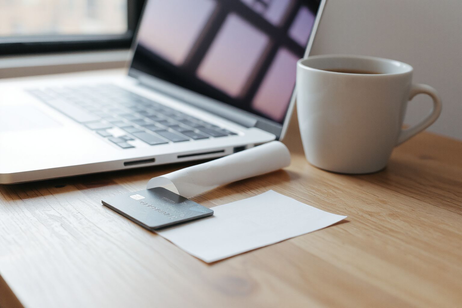 Canada eTA: laptop, coffee mug, and credit card on a wooden desk